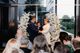 Sylvie officiates the wedding ceremony while the bride and groom holds hands and the audience watches on.
